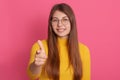 Indoor portrait of pleasant cheerful young lady posing isolated over pink background in studio, smiling sincerely, making gesture