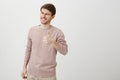 Indoor portrait of pleased handsome young guy showing thumb up, giving positive reply while smiling broadly and winking Royalty Free Stock Photo