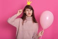 Indoor portrait of pretty brunette woman wearing funny fake crown and rose ready for party holidays time, wearing trendy cozy