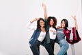 Indoor portrait of pretty international friends funny dancing and waving hands. Adorable asian girl in blue jeans Royalty Free Stock Photo