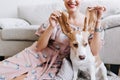 Indoor portrait of smiling woman in romantic pink dress with cute beagle puppy on foreground. Amazing girl with white Royalty Free Stock Photo