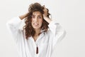 Indoor portrait of stunned anxious woman who do not know what to do and having panic attack, holding hands on hair