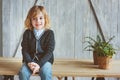Indoor portrait of 5 years old boy with long hair sitting on table Royalty Free Stock Photo
