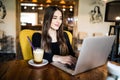 Indoor portrait of a young girl she works as a freelancer in a cafe drinking a delicious hot Cup of coffee from text send mail loa Royalty Free Stock Photo