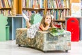 Indoor portrait of young happy smiling girl reading book Royalty Free Stock Photo