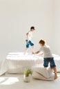 Indoor positive activity. Small children jumping on a bed and having fun in sunshine