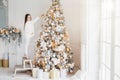 Indoor shot of adorable little kid stands on chair on tiptoes, decorates big New Year tree, has good mood, being in anticipation o Royalty Free Stock Photo