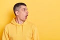 Indoor shot of astonished shocked young adult man wearing casual style hoodie, looking aside with open mouth at copy space for Royalty Free Stock Photo