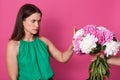 Indoor shot of attractive lady dressed green sundress, refuses beautiful bouquet of white and pink peony flowers from faceless Royalty Free Stock Photo