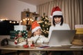 Happy young woman and her girl shopping online on laptop in cozy Christmas interior Royalty Free Stock Photo