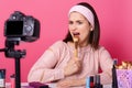 Indoor shot of charismatic artistic young blogger posing in front of camera around cosmetics, holding makeup tool in one hand,