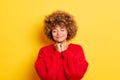 Indoor shot of cute curly haired young lady keeps clenched fists together under chin, dreams with closed eyes, wears Royalty Free Stock Photo