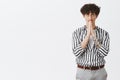 Indoor shot of cute young and stylish jewish guy with dark curly hair moustache and tatoos in striped shirt and pants