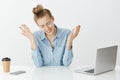 Indoor shot of depressed unhappy european businesswoman in glasses, spreading hands and crying while looking at table