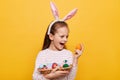 Indoor shot of extremely happy little girl wearing bunny ears holding Easter eggs in wicker basket, winning Easter hunt, screaming Royalty Free Stock Photo