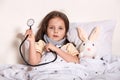 Indoor shot of female child waits for pediatrician doctor for examining little girls heart lungs to check for problems, charming