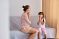 Indoor shot of female speech therapist working with little girl, training pronunciation of sounds and articulation, people wearing
