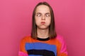 Indoor shot of funny positive woman wearing casual jumper standing isolated over pink background, posing with crossed eyes and Royalty Free Stock Photo