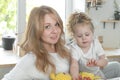 Indoor shot of good looking blond mother and her small daughter gives hug, enjoy domestic atmosphere