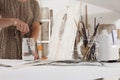 Indoor shot of half length cropped body and hands with no head of female artist in bright white studio while cleaning brushes wear