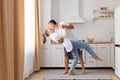 Indoor shot of handsome dark haired man and attractive young adult woman having fun together in the kitchen, romantic couple is Royalty Free Stock Photo