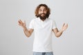 Indoor shot of handsome excited eastern man with curly hair and beard shaping or gesturing while talking with friend