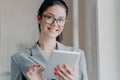 Indoor shot of happy brunette entrepreneur reads electronic book on modern digital tablet, reads financial news in internet during