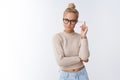 Indoor shot of influental attractive and sassy confident female boss in glasses rolling strand of blond hair on finger