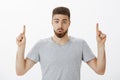 Indoor shot of interested and intrigued handsome masculine man with beard and brown hairstyle folding lips from