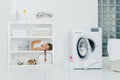 Indoor shot of little girl has sleep on console with favourite dog, has rest in laundry room with washing machine filled of linen