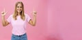 Indoor shot of pleasant attractive friendly-looking girl with tanned skin in casual t-shirt and jeans raising hands