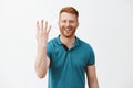 Indoor shot of pleased and satisfied male redhead client with bristle in green polo shirt showing number four with