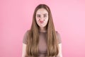 Indoor shot: a pretty brunette girl looks at the camera with a dubious and indecisive expression on her face chasing her lips as