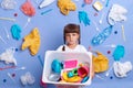 Indoor shot of sad upset little girl wearing white t shirt, throwing away her plastic toys, saving environment, posing against Royalty Free Stock Photo