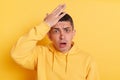 Indoor shot of shocked scared man wearing casual style hoodie, posing isolated over yellow background, looking at camera with open Royalty Free Stock Photo