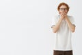 Indoor shot of shocked and scared speechless redhead young male with beard panicking or being terrifyed with shocking