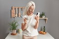 Indoor shot of shocked surprised woman wrapped in towel wearing white T-shirt standing in kitchen, drinking her morning coffee, Royalty Free Stock Photo