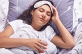 Indoor shot of sleeping girl with blindfold on her head, female wearing white t shirt, lying in bed under blanket, keeps eyes Royalty Free Stock Photo