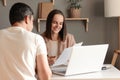 Indoor shot of smiling businesswoman working with new partner, showing documents, sitting at table in office in front of laptop, Royalty Free Stock Photo