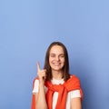 Indoor shot of smiling smart clever woman wearing casual style clothing, raised finger up, having an idea, looking at camera with Royalty Free Stock Photo