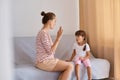 Indoor shot of speech pathologist having lesson with little girl, teacher demonstrates how to pronaunce sounds in correct way,