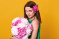 Indoor shot of sweet adorable young lady enjoying bouquet of flowers, satisfied with spring present, feeling smell of peonies,