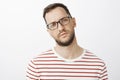 Indoor shot of unfocused sleepy male model in black glasses, squinting and being tired, having no idea what is happening