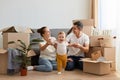 Indoor shot of wife and husband posing in their new apartment on moving day, family with baby relocating in a new house and feels Royalty Free Stock Photo