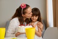 Indoor shot of woman with female kid celebrating birthday, mother kissing her little daughter, congratulating child with her Royalty Free Stock Photo