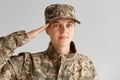 Indoor shot of young adult attractive woman army soldier saluting, looking at camera with serious facial expression, wearing Royalty Free Stock Photo