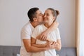 Indoor shot of young attractive couple, hugging and kissing, expressing happiness, gentle and love, being happy to spend time