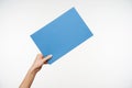 Indoor shot of young female`s elegant hand being raised while keeping piece of light blue paper in it, passing it to someone whil