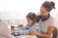 Indoor shot of young mother and child with laptop on white background, family playing computer games together, mommy wears casual Royalty Free Stock Photo