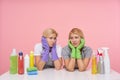 Indoor shot of young wailful blonde cleaning ladies holding their faces with raised hands and looking sadly on each other, having